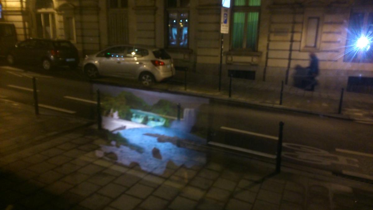 Reflection of Kalulu Falls lightbox on Rue de Namur